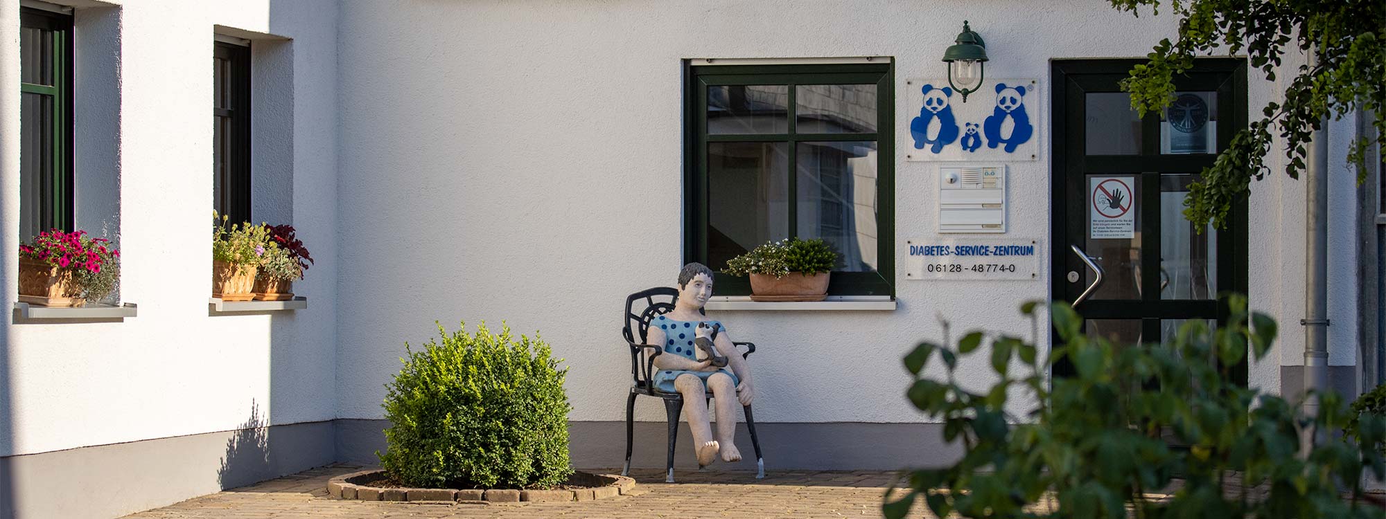 Über einen Hof gelangt man zum Eingang. Blumenkästen mit verschienen Pflanzen auf Fensterbänke.