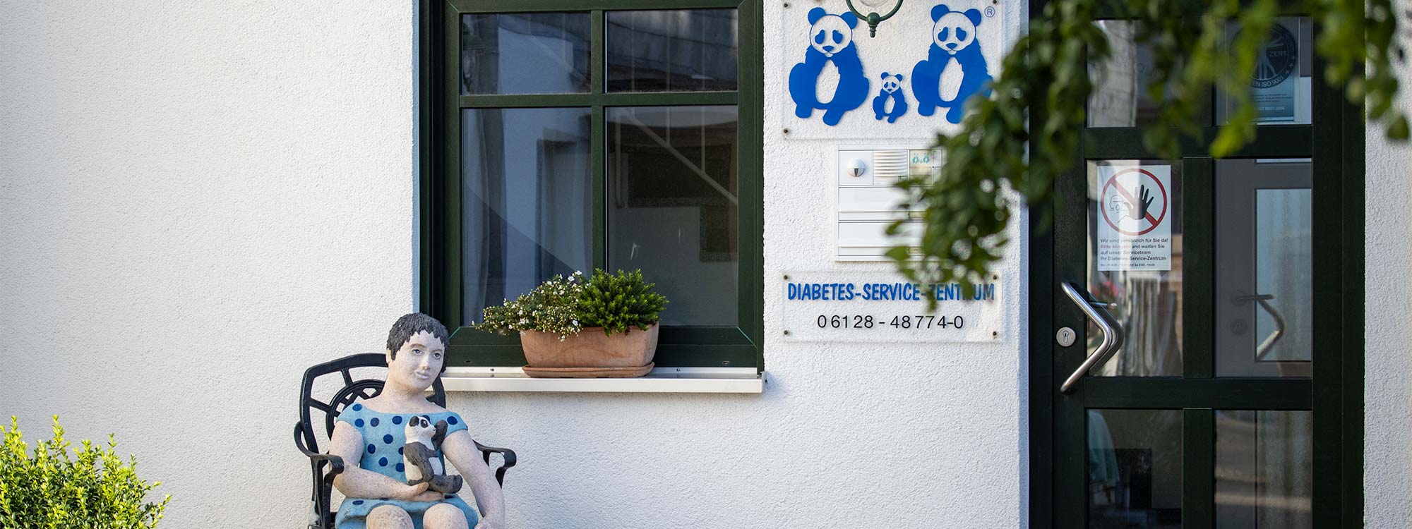Der Eingang wird flankiert von einer Figur die auf einem Stuhl sitz.